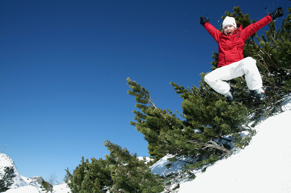 Junge macht Luftsprung im Schnee, See, Tirol, Österreich