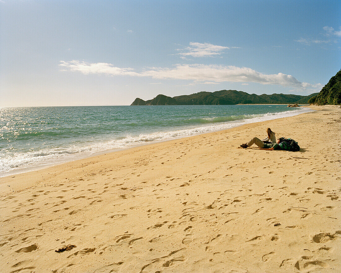Menschen liegen am Waiharakeke Beach in der Sonne, Abel Tasman Nationalpark, Nordküste, Südinsel, Neuseeland