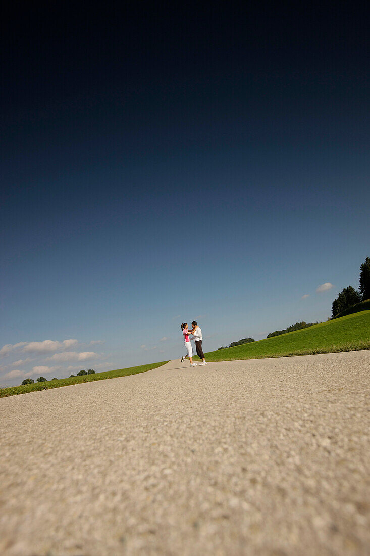 Paar steht auf Landstraße, Münsing, Bayern, Deutschland