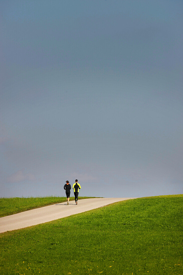 Couple jogging along road, Munsing, Bavaria, Germany
