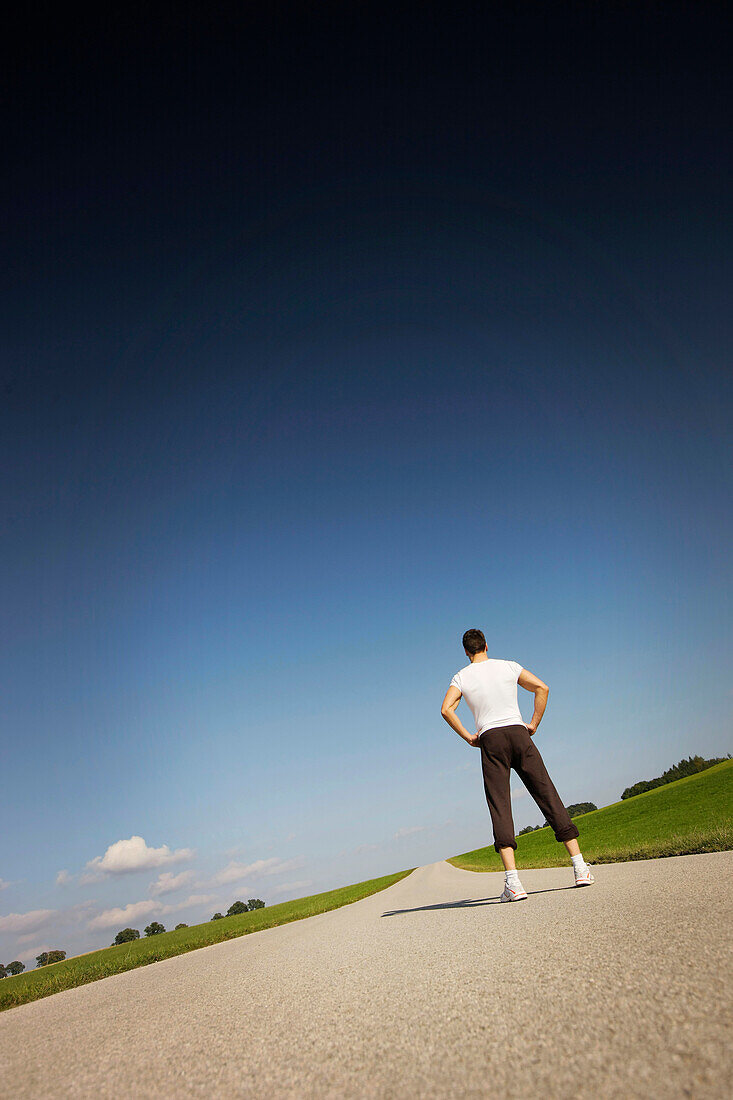 Jogger auf einer Landstraße, Münsing, Bayern, Deutschland