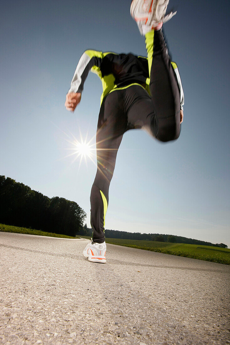 Mann joggt über Landstraße, Straßlach-Dingharting, Bayern, Deutschland