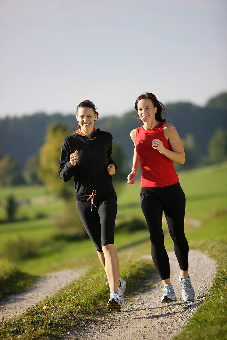 Zwei Frauen joggen über Feldweg, Münsing, Bavaria, Germany