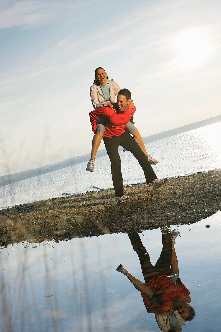 Man giving woman piggyback, Ambach, Bavaria, Germany