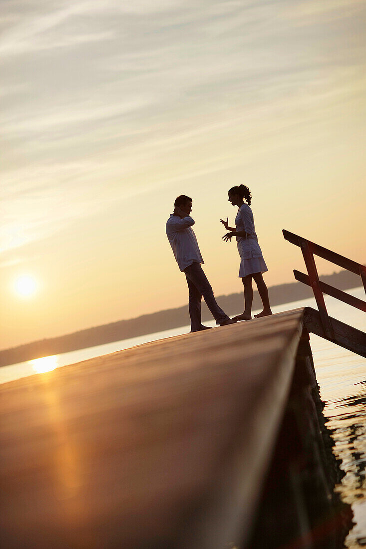 Couple standing on a jetty a Lake Starnberg, Ambach, Bavaria, Germany