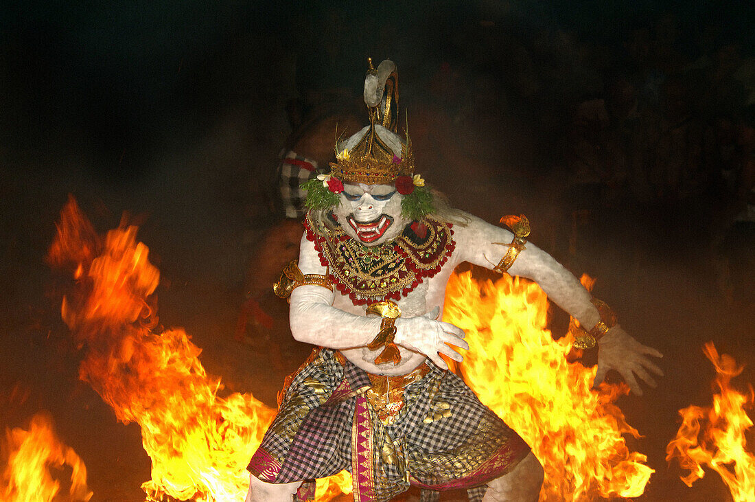 Male Balinese dancer wearing a mask used in the traditional Kecak dance which is based on a sanghyang (trance ) chorus formaly used in times of epidemic. Scene shows fire finale.