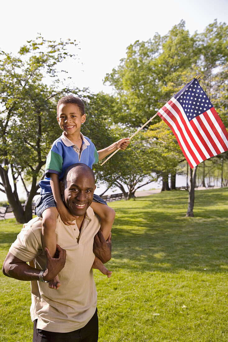 Afroamerikaner, Aktivität, Amerika, amerikanische Fahne, Auf dem Rücken, Auf Schulter, Aussen, Bande, Blick Kamera, Draussen, Erholen, Erholung, Erwachsene, Erwachsener, Ethnisch, Fahne, Fahnen, Familie, Familien, Farbe, Flagge, Flaggen, Freizeit, Freude,