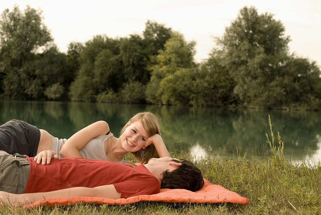 Junges Paar liegt auf einer Decke am Seeufer, Freising, Bayern, Deutschland