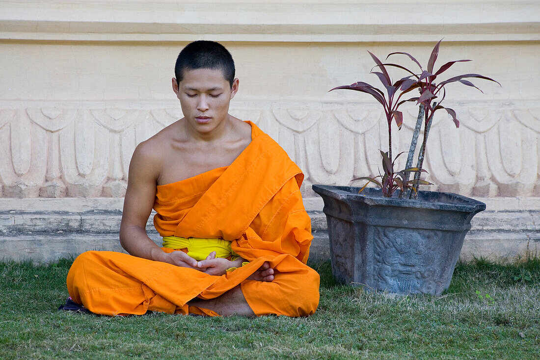 Buddhistischer Mönch sitzt vor dem Kloster Vat Pa Phonphao, Luang Prabang, Laos