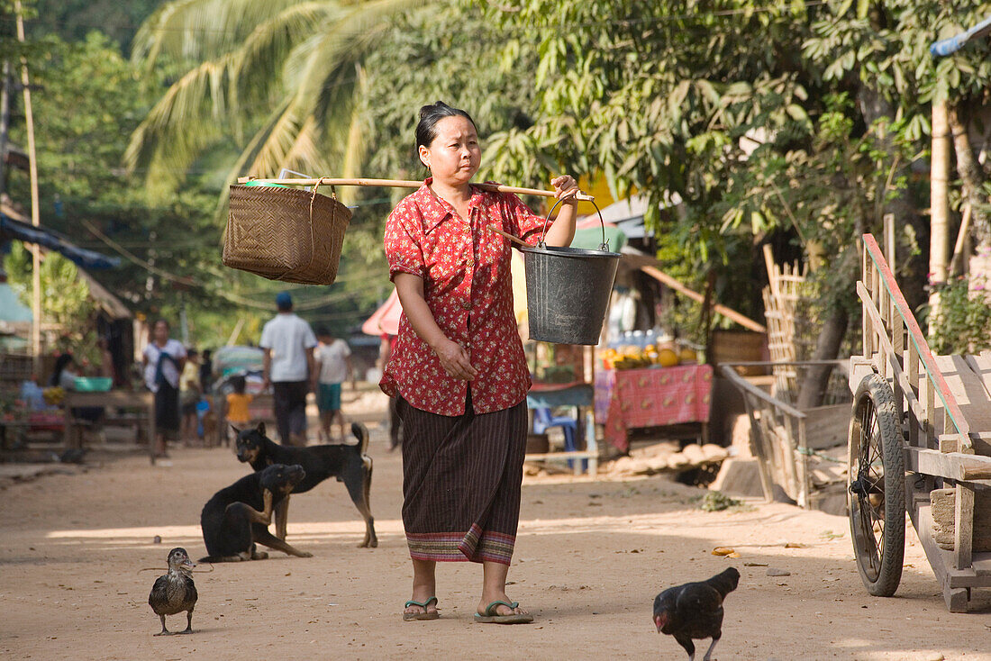Laotische Frau trägt Lasten im Fischerdorf Muang Ngoi Kao, Provinz Luang Prabang, Laos