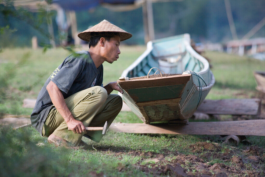 Ein Fischer repariert sein Boot im Fischerdorf Muang Ngoi Kao, Provinz Luang Prabang, Laos