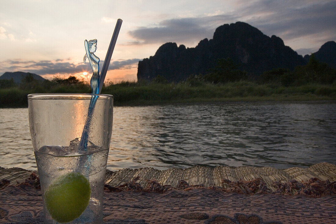 Sundowner Cocktail am Ufer des Flusses Nam Xong bei Sonnenuntergang, Vang Vieng, Provinz Vientiane, Laos