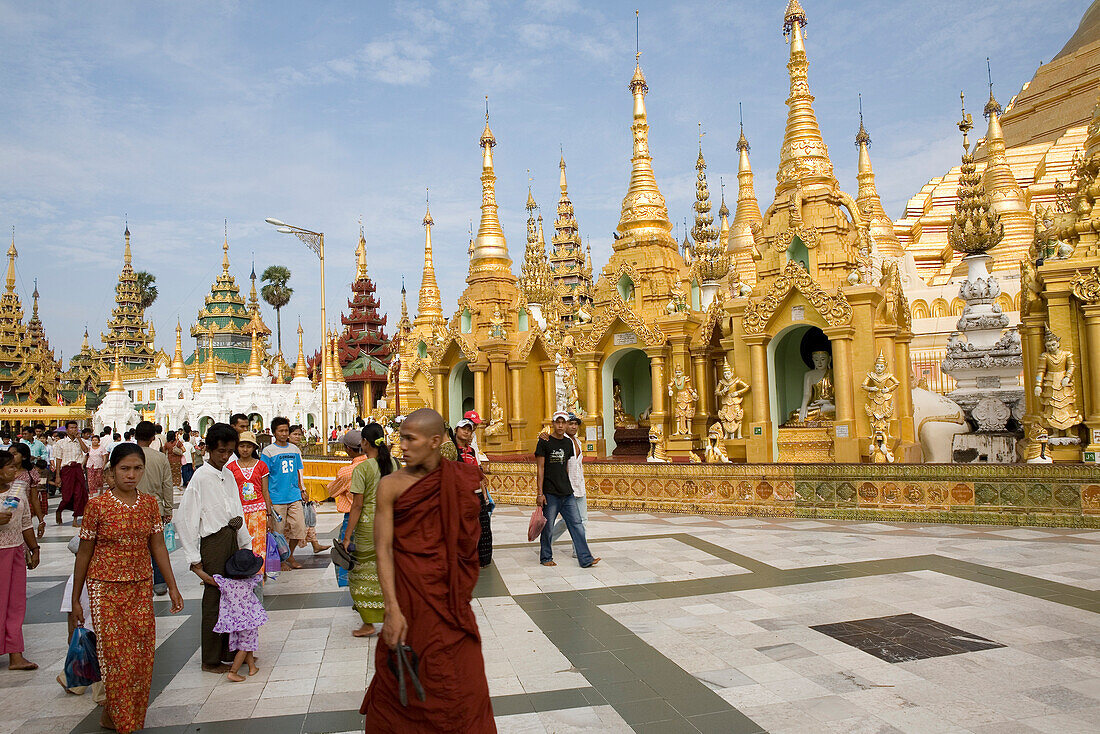 Buddhistischer Mönch und Touristen vor goldenen Stupas in der Anlage der Shwedagon Pagode in Yangon, Rangun, Myanmar, Burma