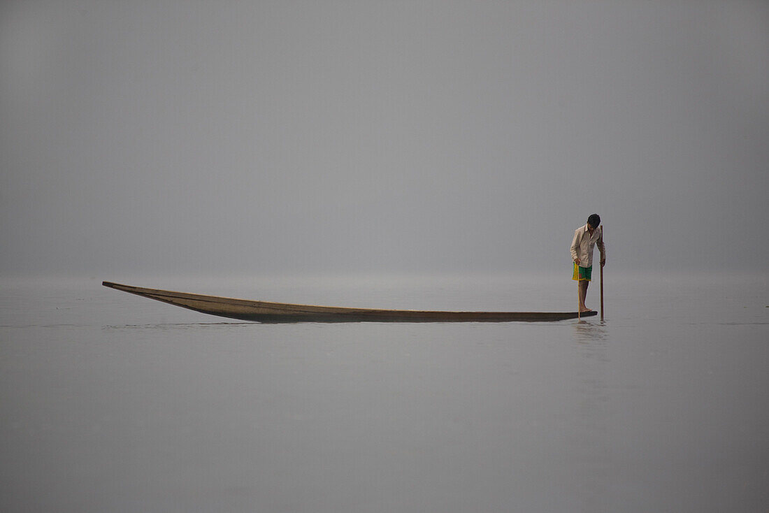Intha fisherman standing on his fishing boat on Inle Lake, Shan State, Myanmar, Burma