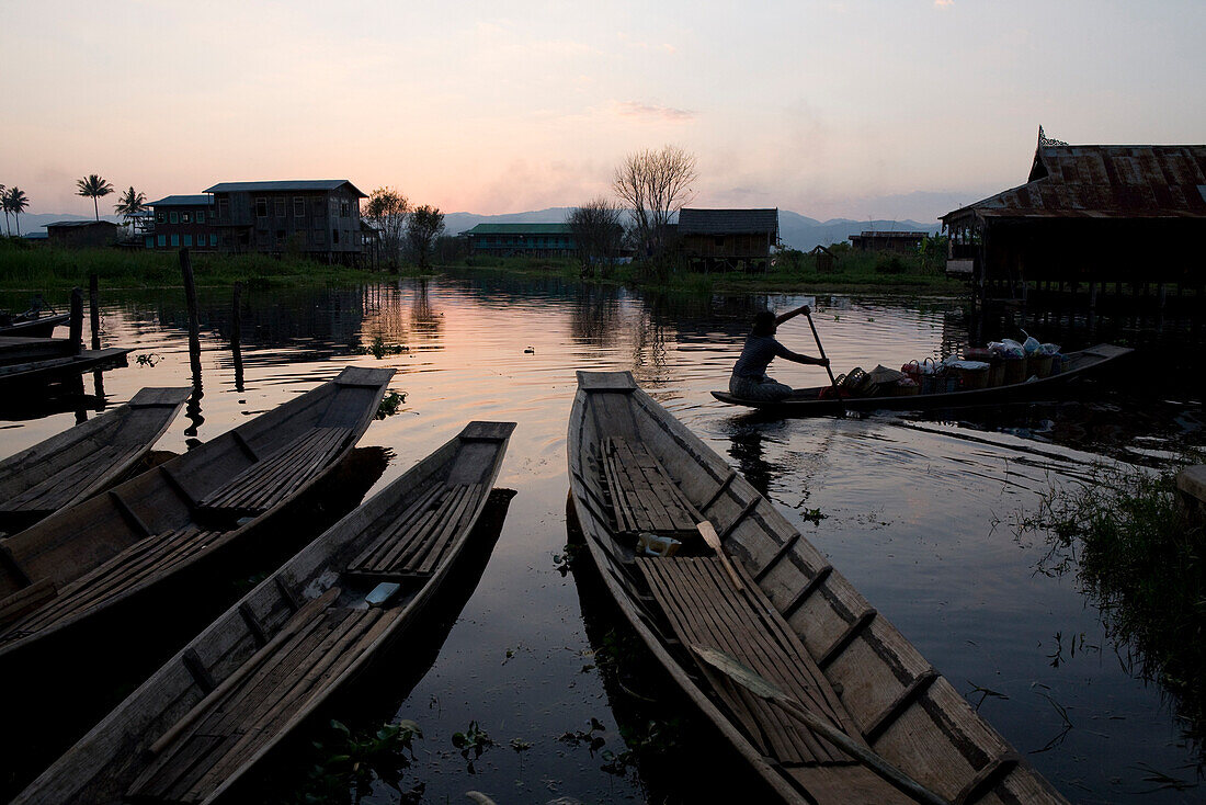 Canoes and women in a canoe at dusk at Inle Lake, Shan State, Myanmar, Burma