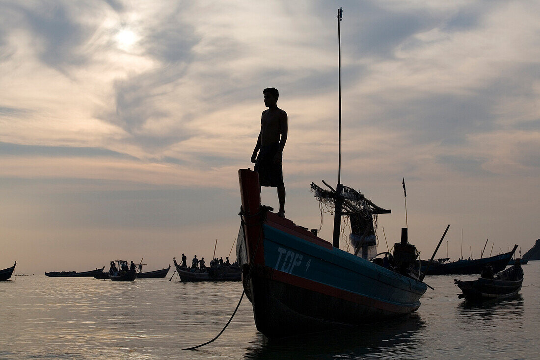 Mann auf Fischerboot bei Sonnenuntergang in Ngapali Beach, am Golf von Bengalen, Rakhine-Staat, Myanmar, Burma