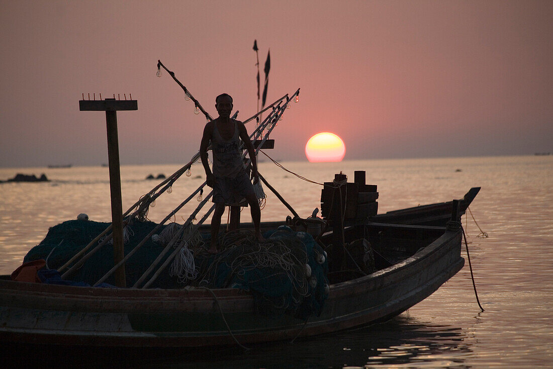 Mann auf Fischerboot im Sonnenuntergang in Ngapali Beach, am Golf von Bengalen, Rakhine-Staat, Myanmar, Burma