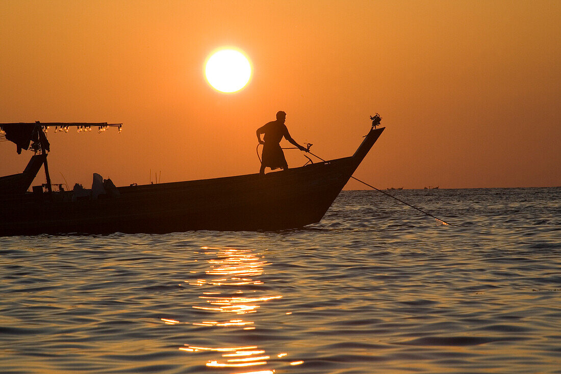Mann auf Fischerboot im Sonnenuntergang in Ngapali Beach, am Golf von Bengalen, Rakhine-Staat, Myanmar, Burma