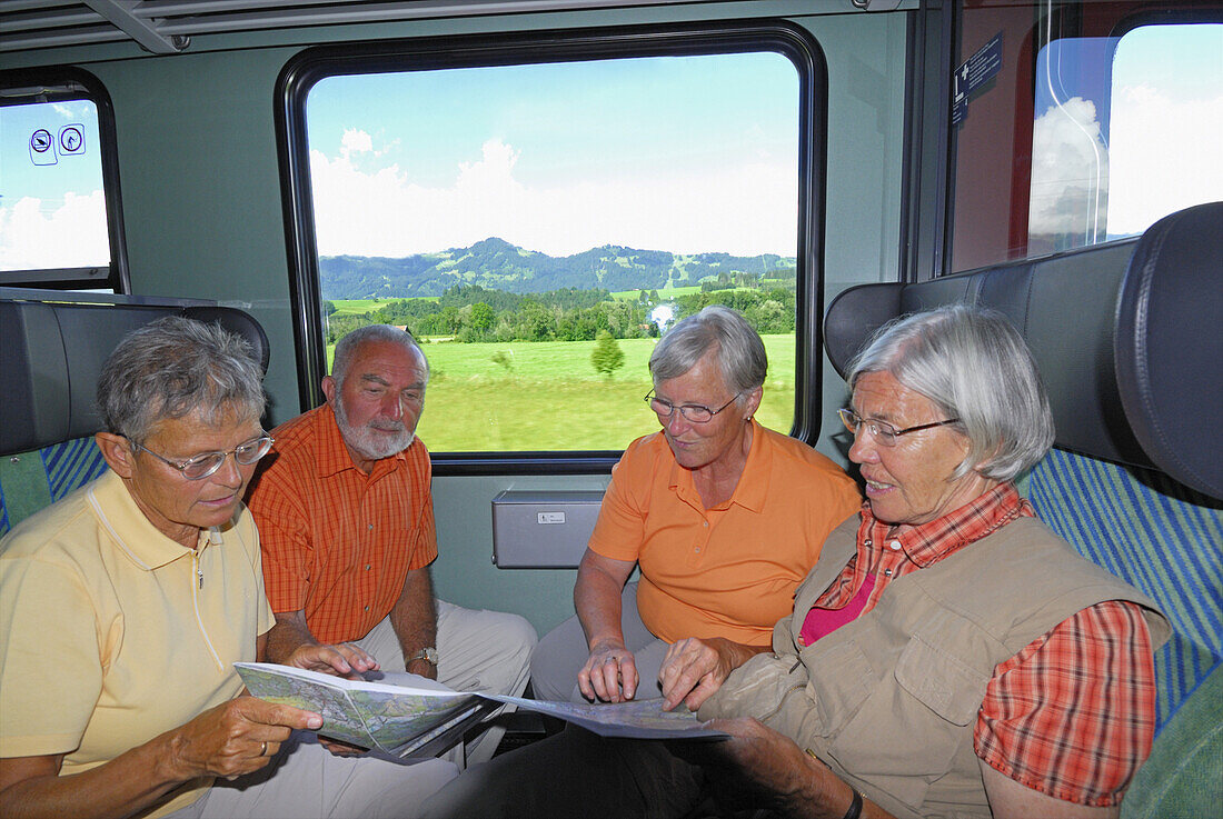 Gruppe Senioren mit einer Landkarte im Zug, Allgäu, Bayern, Deutschland