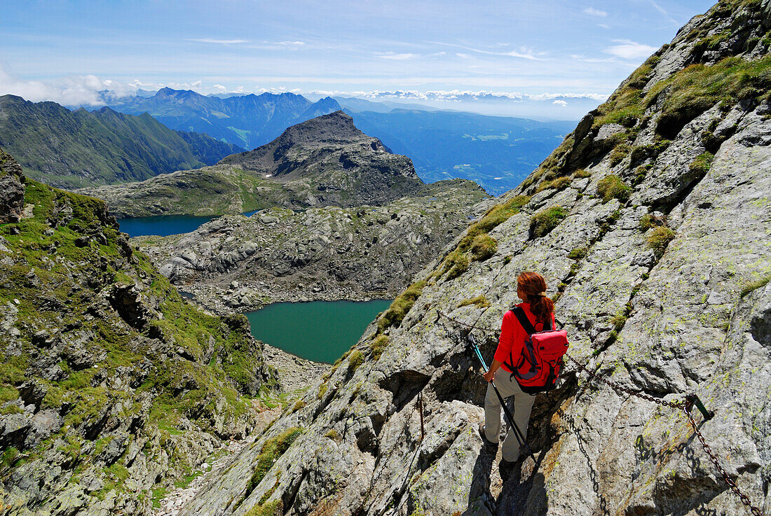 young woman descending from notch Milchseescharte to Spronser Seenplatte with lake Langsee and lake Milchsee and Große Rötelspitze, Texelgruppe range, Ötztal range, South Tyrol, Italy