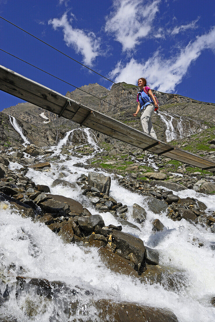 Woman on a bridge crossing stream, National Park Hohe Tauern, Salzburg, Austria