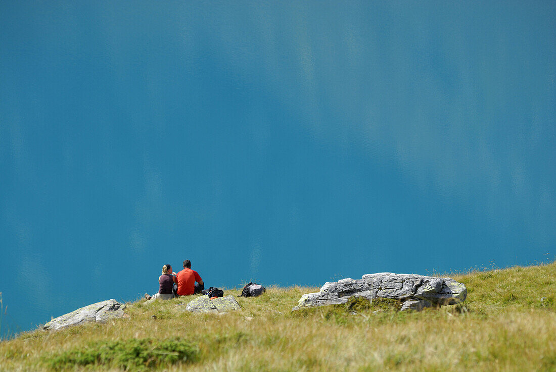 Couple resting at lake Gruenau, Stubai Alps, Stubai, Tyrol, Austria