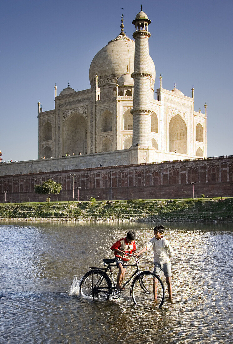 Boys playing with bike in front of the Taj Mahal, Agra. Uttar Pradesh, India