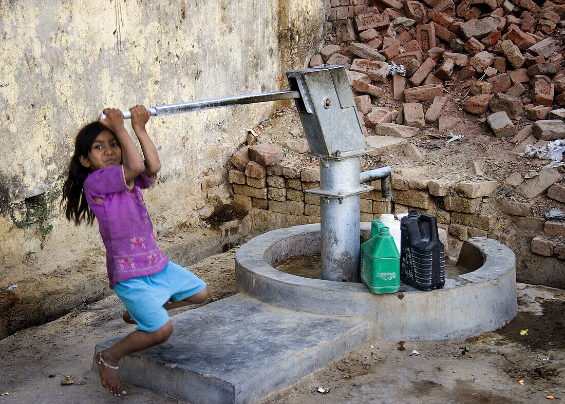 Girl pumping water from well, Allahabad. Uttar Pradesh, India