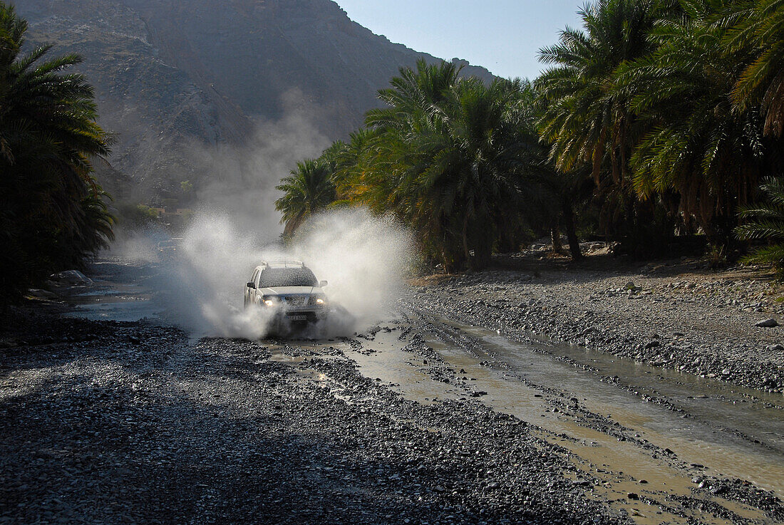 Ein Geländewagen fährt durch ein Flussbett, Al Hajar Berge, Wadi Bani Auf, Oman, Asien