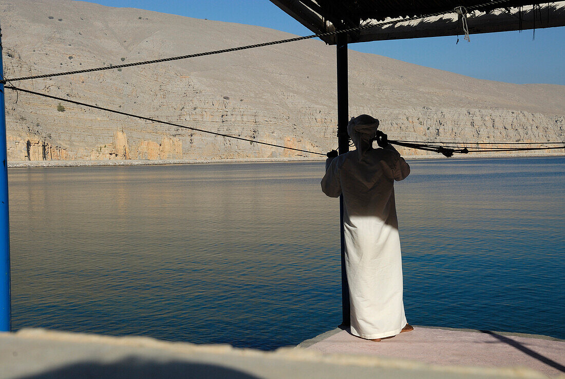 Einheimischer Fischer steht am Wasser, Al Hajar Berge, Musandam, Oman, Asien