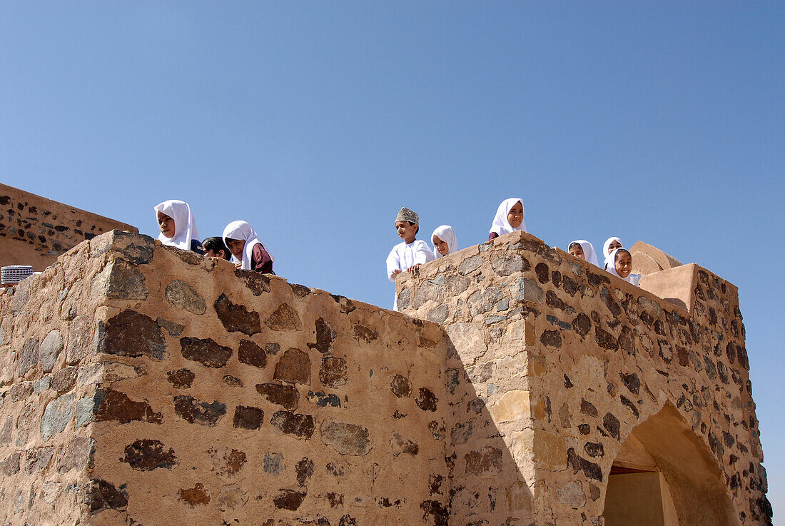 Einheimische Kinder betrachten die Aussicht von den Zinnen von Fort Jabrin, Oman, Asien