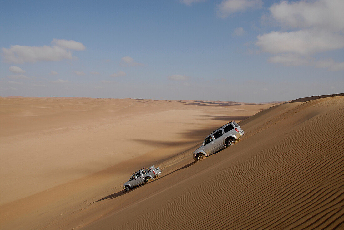 Zwei Geländewagen fahren eine Sanddüne hinunter, Wahiba Sands, Oman, Asien