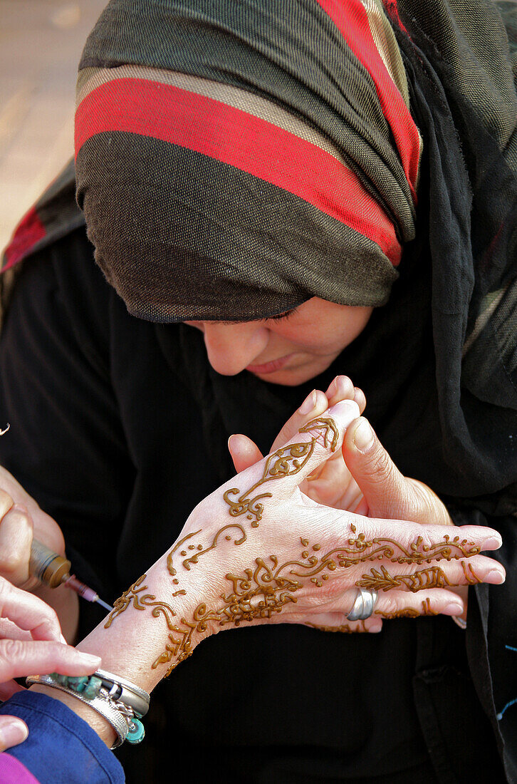 Einheimische bemalt die Hand einer Touristin mit Henna, Place Djamâa el-Fna, Marrakesch, Marokko, Afrika