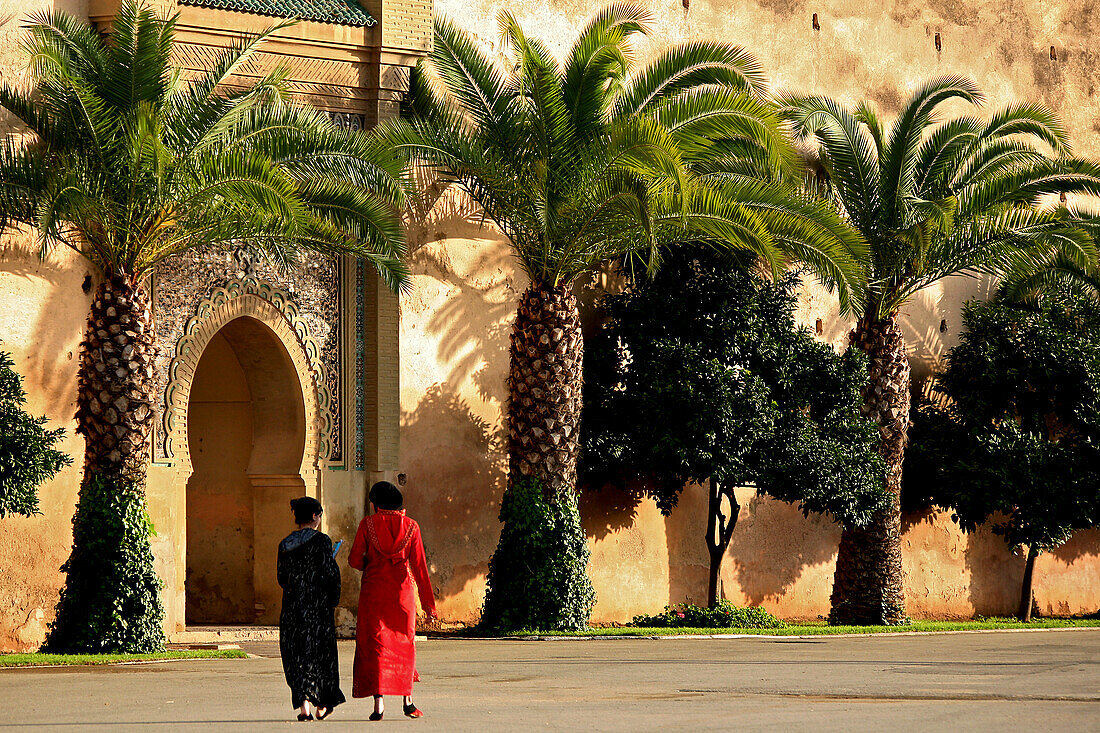 Two moroccan women in front of the fortification wall of the royal palace Dar el Makhezen, Meknes, Morocco, Africa