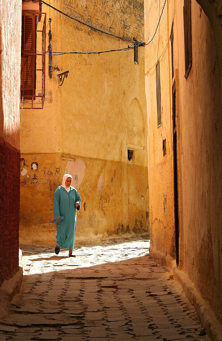 Moroccan woman at an alley of Meknes' medina, Meknes, Morocco, Africa