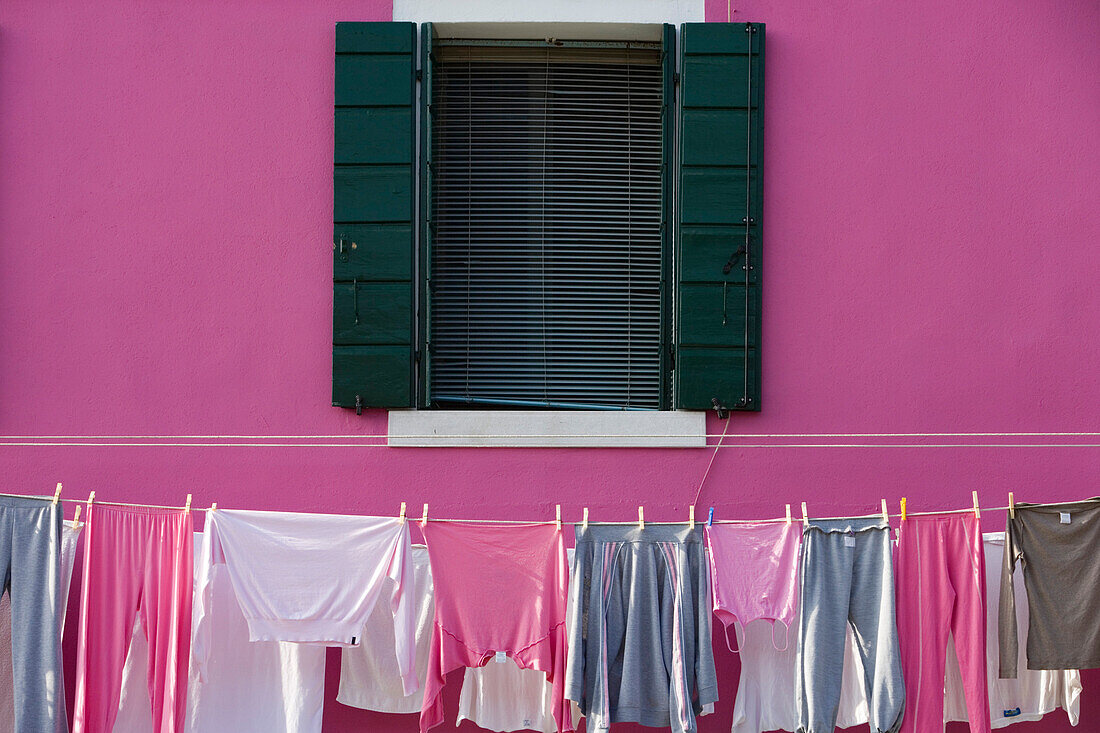 Pink and grey laundry drying on a washing line outside a pink painted house, Burano, Veneto, Italy