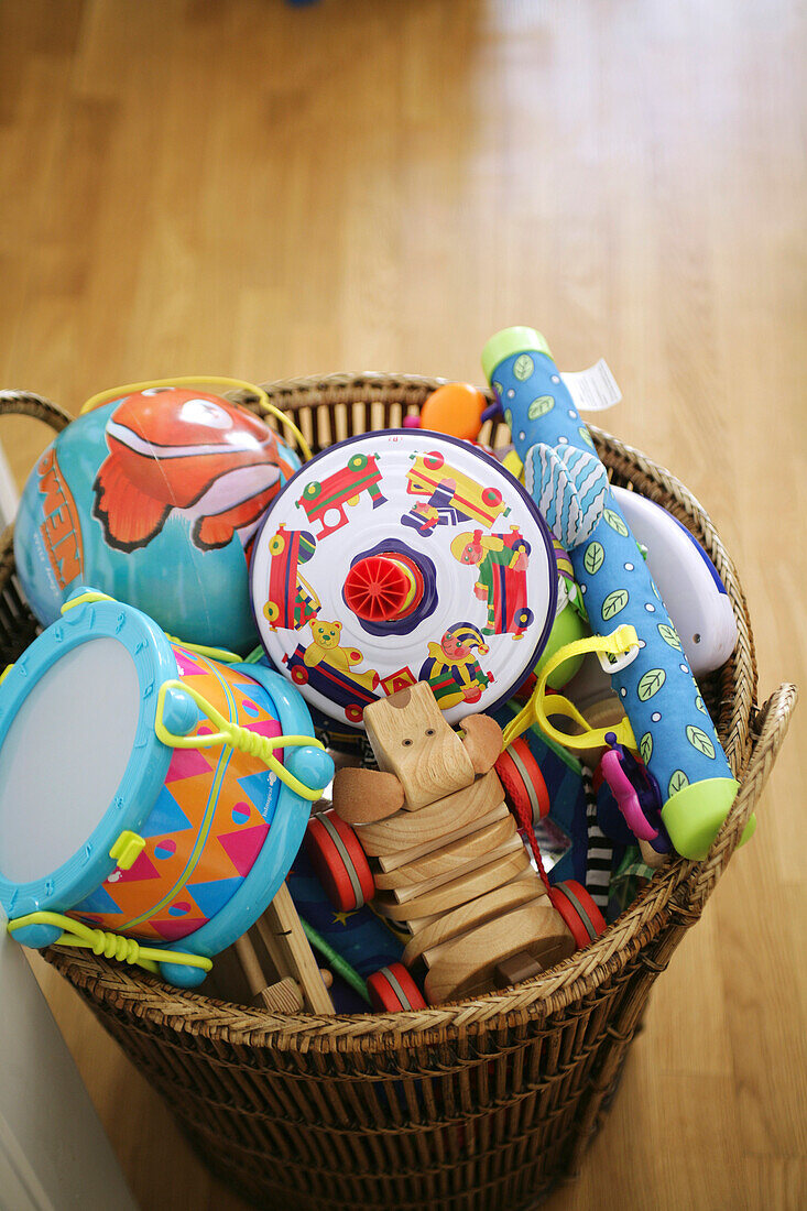 Different toys for little children in a basket on parquet