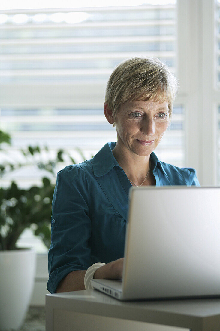 Ältere Frau arbeitet an einem Laptop