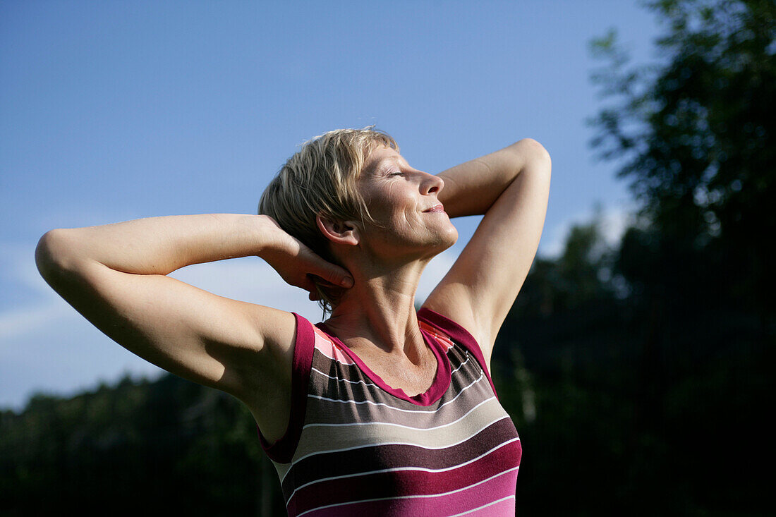 Mature woman stretching in sun, Styria, Austria