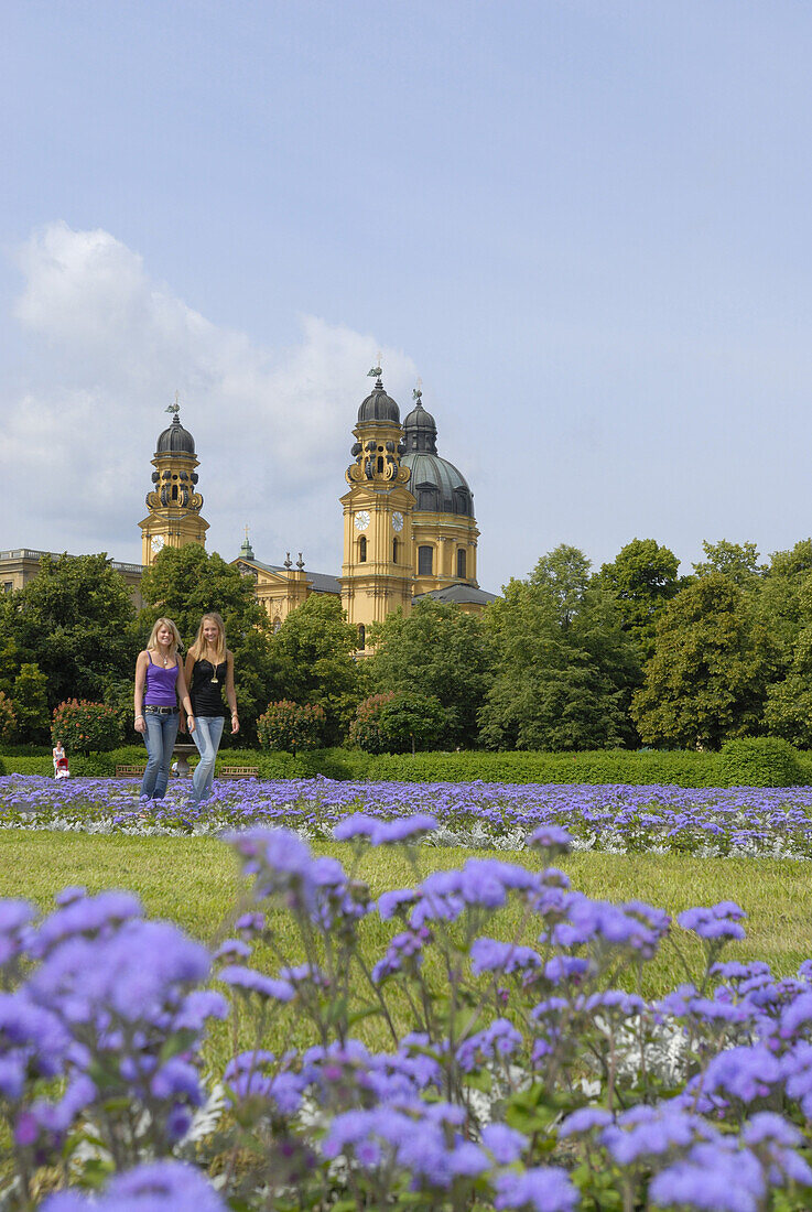 Two young women in Hofgarten, Theatine Church in background, Munich, Bavaria, Germany