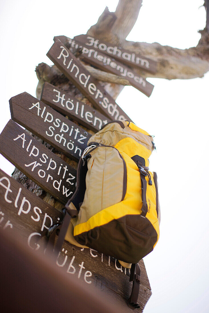 Rucksack hängt an einem Wegweiser, Wettersteingebirge, Bayern, Deutschland