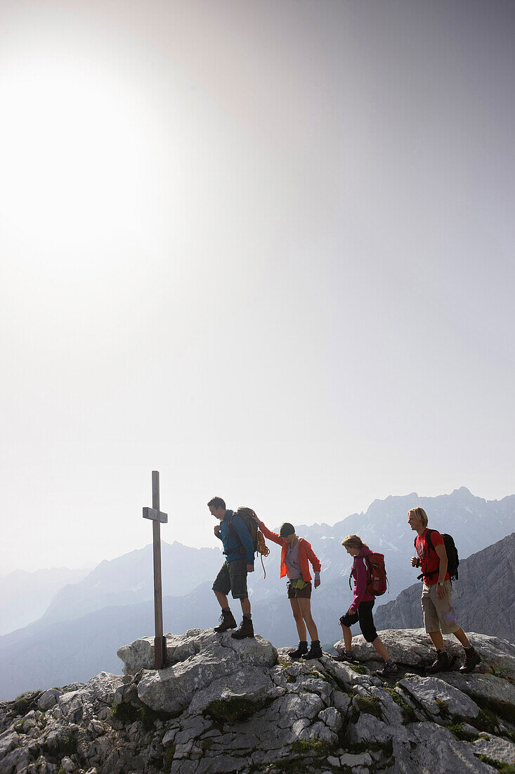 Hikers near summit cross, Wetterstein range, Bavaria, Germany