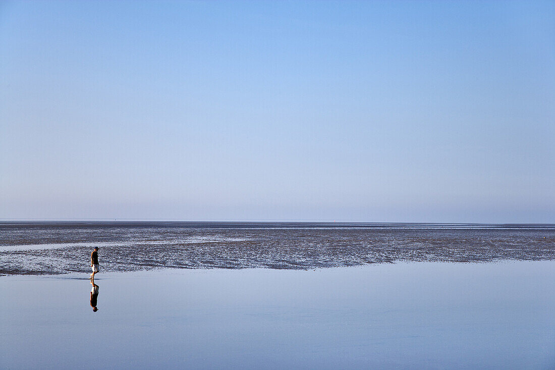 Person walking through mudflat, Pellworm island, Schleswig-Holstein, Germany