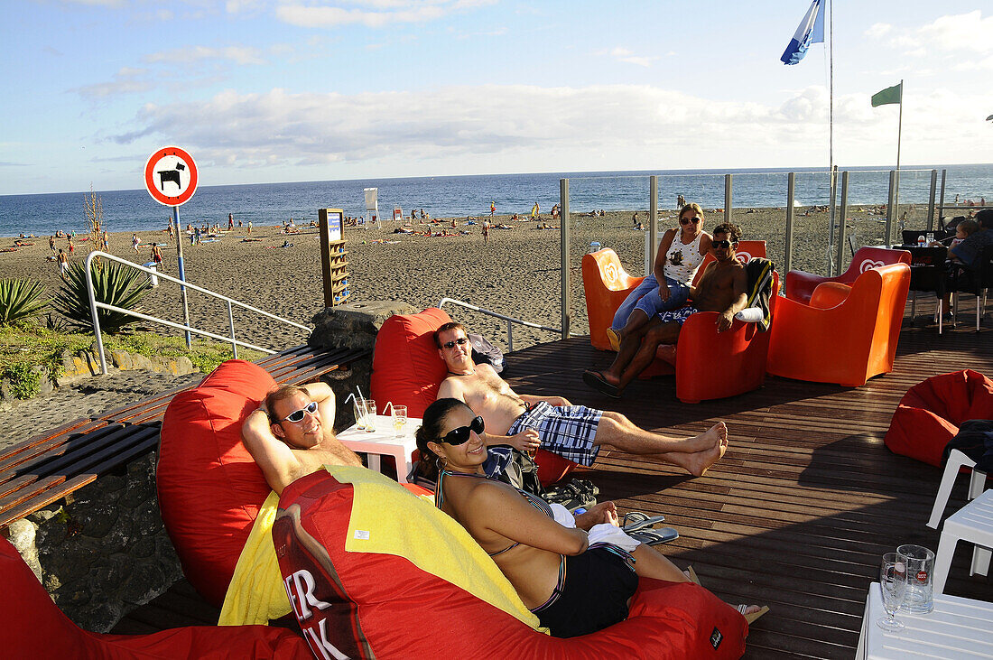 People sitting at a beach bar at do Populo beach, near Ponta Delgada, Sao Miguel, Azores, Portugal