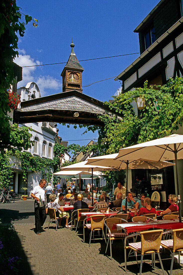 Menschen auf der Terrasse eines Weinlokals im Sonnenlicht, Winningen, Rheinland-Pfalz, Deutschland