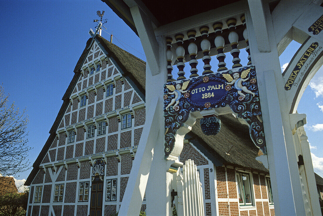 Kunstvoll verziertes Hoftor vor reetgedecktem Fachwerkhaus, Altes Land, Niedersachsen, Deutschland