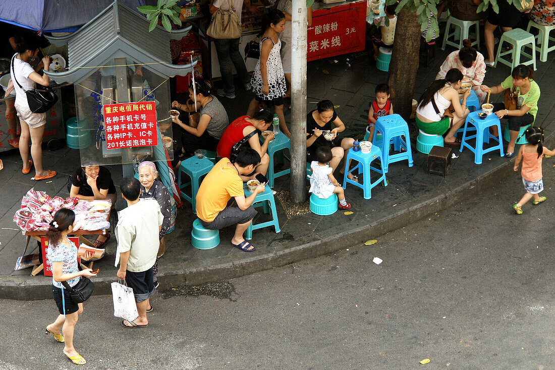 People sitting and eating at a streetrestaurant in Chongqing, China, Asia