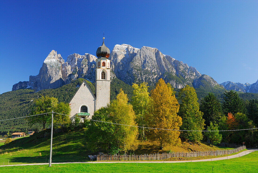 Kirche St. Konstantin mit herbstlich verfärbten Bäumen unter dem Schlern, Dolomiten, Südtirol, Italien