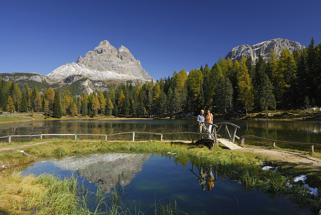 Couple at lake Antornosee, Tre Cime di Lavaredo in background, Dolomites, South Tyrol, Italy