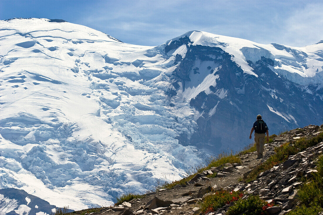 A hiker in front of snow covered mountain, Burroughs Mountain Trail, Mount Rainier Nationalpark, Washington, USA